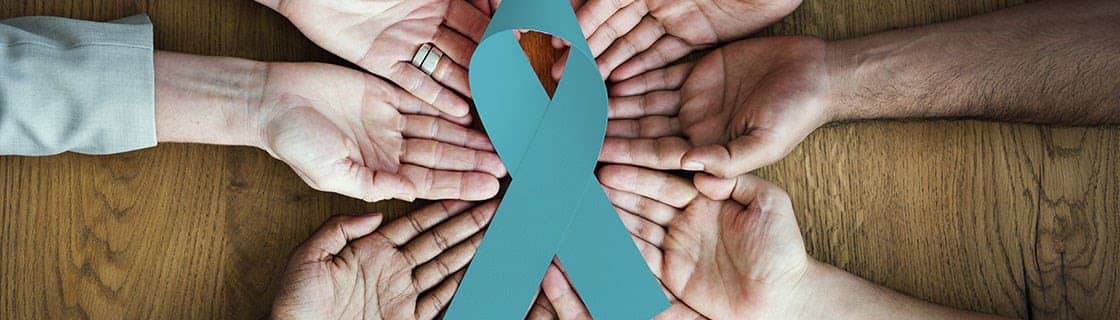 Photograph of several people's open hands around a ribbon Photograph of several people's open hands around a ribbon