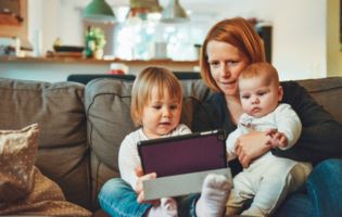 Mother with Two Children Sitting on a Couch and Looking at a Tablet Mother with Two Children Sitting on a Couch and Looking at a Tablet