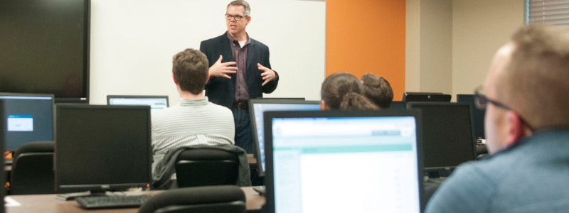 Teacher in Front of Room of Computers and Students Teacher in Front of Room of Computers and Students