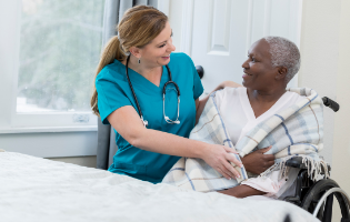 Female CNA Assisting a Female Patient in Wheelchair Female CNA Assisting a Female Patient in Wheelchair