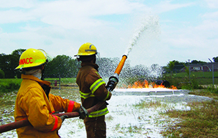 Two 火灾科学 students holding a hose pointed towards a fire