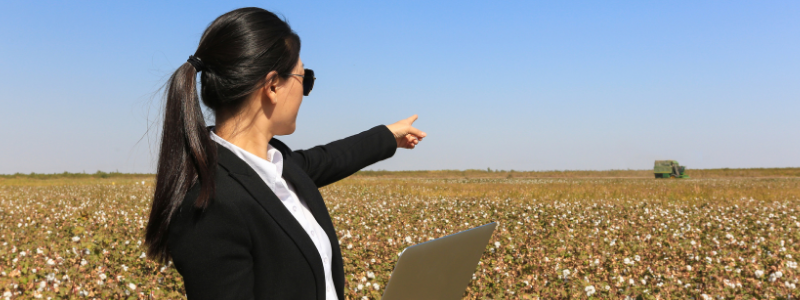 Woman Holding Laptop and Pointing to a Field of Crops Woman Holding Laptop and Pointing to a Field of Crops