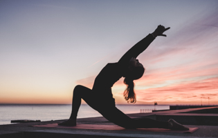 silhouette of a woman doing yoga on the beach