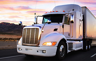 White eighteen wheel truck on the road at dusk