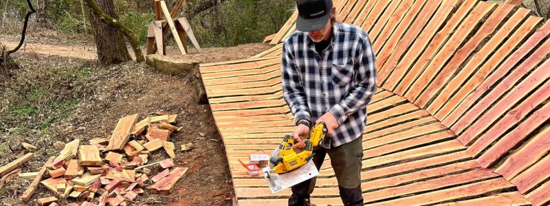 Man Holding Power Tool and Standing on a Trail with Wooden Planks Man Holding Power Tool and Standing on a Trail with Wooden Planks