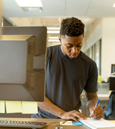Man in Front of Computer and Writing on Paper Man in Front of Computer and Writing on Paper